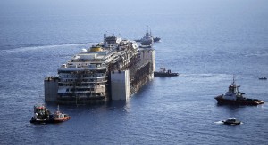 Tugboats drag the cruise liner Costa Concordia as they leave Giglio Island