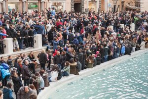 Rome Italy - February 13 2016: Tourists visiting the Trevi Fountain an iconic symbol of Imperial Rome. It is one of the most popular tourist attractions in Rome